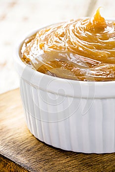 pot of dulce de leche or homemade caramel on rustic wooden background, typical Brazilian sweet