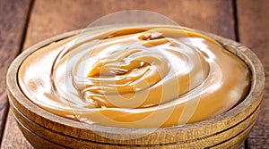 pot of dulce de leche or homemade caramel on rustic wooden background, typical Brazilian sweet