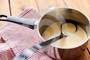 Pot with eggnog and ladle on kitchen towel