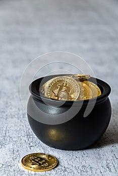 Pot of gold bitcoins on a white and gray crackle background, one coin on background