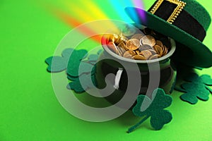 Pot with gold coins, hat and clover leaves on green background. St. Patrick`s Day celebration