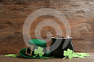 Pot of gold coins, hat and clover leaves on table, space for text. St. Patrick`s Day celebration