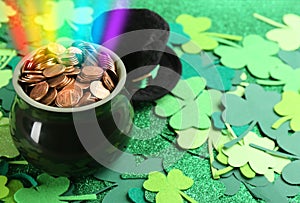 Pot with gold coins, hat and clover leaves on table, space for text. St. Patrick`s Day celebration