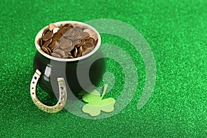 Pot of gold coins, horseshoe and clover on green, space for text. St. Patrick`s Day celebration