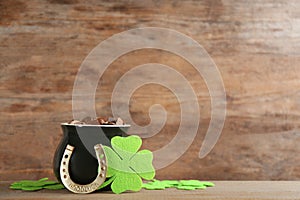 Pot of gold coins, horseshoe and clover leaves on table, space for text. St. Patrick`s Day celebration