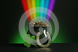 Pot with gold coins, horseshoe and clover on table against dark background. St. Patrick`s Day