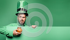 Pot of gold. Green patricks background. Man in Saint Patrick`s Day leprechaun party hat having fun on green background. photo