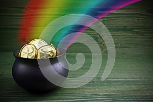 Pot Of Gold on green woden background. Magical Treasure with Rainbow