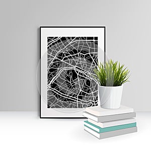 A pot of green grass stands on a pack of books near a picture with a black map. Home office concept, study or freelance