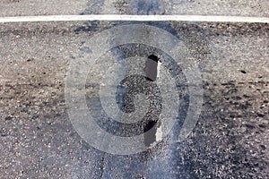 A pot hole in the asphalt road in need of maintenance