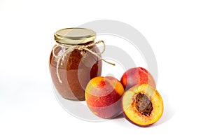 Pot of jam on white background with ripe appetizing half cut peaches