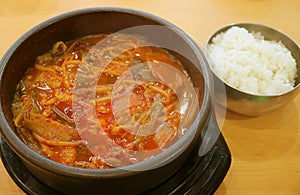 Pot of Kimchi Jjigae or Korean Hot and Spicy Kimchi Stew Served with a Bowl of Rice on Wooden Table