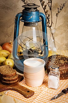 Pot of milk, rye bread and a kerosene lantern on the table