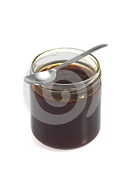 Pot of Molasses with Spoon against White Background