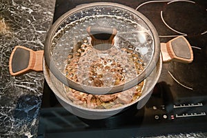 The pot is placed on an electric kitchen stove with the lid open