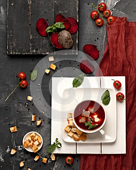 Pot of Red borscht with sour cream and white bread croutons. Portion of Meat soup with tomato, beetroots and mint on