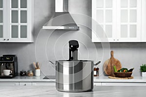 Pot with sous vide cooker on table in kitchen. Thermal immersion circulator