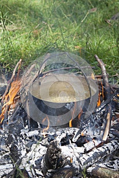 A pot of water is heated on a fire made of branches.