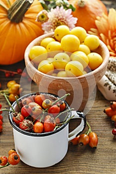 Pot of yellow plums and pot of rose hip, flowers and pumpkins