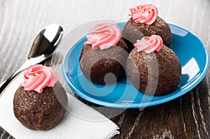 Potato cakes with pink cream in saucer, teaspoon, cake on tissue on wooden table