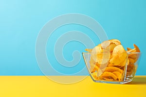 Potato chips. Beer snacks on yellow background against blue background