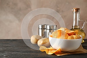 Potato chips in a bowl on craft paper. Potato, spice, olive oil on wooden background