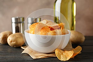 Potato chips in a bowl on craft paper. Potato, spice, olive oil on wooden background, space for text