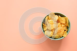 Potato chips in a bowl on a pastel pink background. View from above, copy space