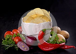 Potato chips on a dark wooden board. Fast food. Dark background