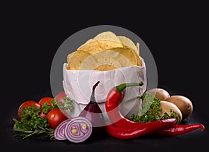 Potato chips on a dark wooden board. Fast food. Dark background