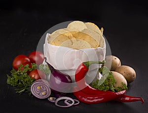 Potato chips on a dark wooden board. Fast food. Dark background