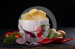 Potato chips on a dark wooden board. Fast food. Dark background