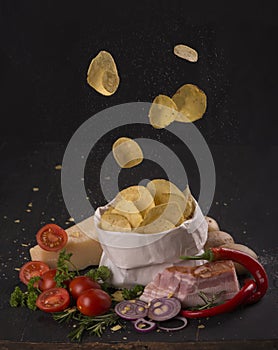 Potato chips on a dark wooden board. Fast food. Dark background