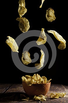 Potato chips falling into an orange ceramic bowl