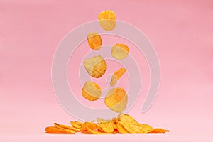 Potato chips fly on a pink background. Levitation.