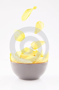 Potato chips flying in gray bowl on white background