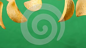 Potato chips in free fall on a green background. Slow motion. Pringles