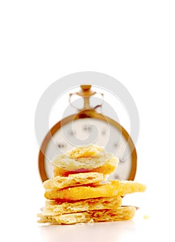 Potato chips in front of vintage pocket clock. time and food concept