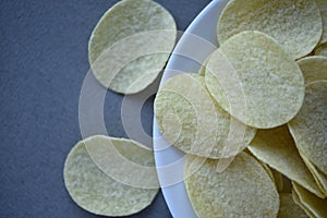Potato chips on a gray background. Pour the chips into a saucer. A delicious snack
