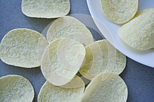 Potato chips on a gray background. Pour the chips into a saucer. A delicious snack