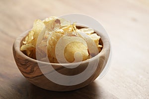 Potato chips with herbs in wood bowl on rustic table