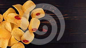 Potato chips with hot peppers on wood background top view with copy space