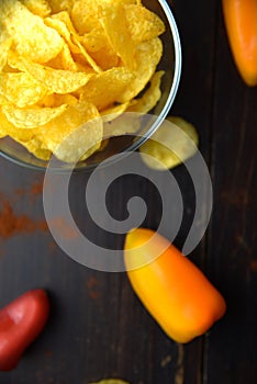 Potato chips with paprika on dark wooden background