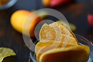 Potato chips with paprika on dark wooden background