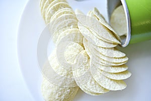 Potato chips in a saucer on a white background. They pour the chips out of the box. A delicious snack