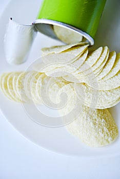 Potato chips in a saucer on a white background. They pour the chips out of the box. A delicious snack