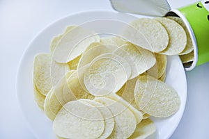 Potato chips in a saucer on a white background. They pour the chips out of the box. A delicious snack