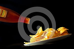 Potato chips with spicy sauce on a black background