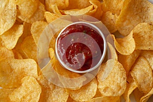 Potato chips with tomato dipping sauce, top view.