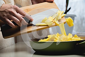 Potato cooking concept, side view. Shot of a young caucasian housewife frying thinly sliced potatoes in a frying pan